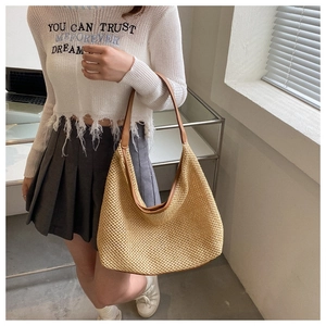 Detail of khaki woven straw shoulder bag with delicate hollow-out craft and thin brown strap