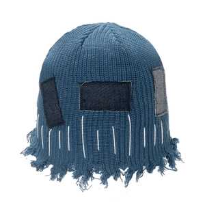 Detail of blue-grey knit beanie featuring distressed denim patches and fringe edges