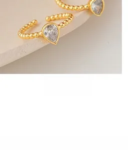 Macro view of 18K gold teardrop zircon rings with unique beaded textured open bands