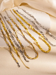 Detail view of woven snake bone necklaces with lobster clasp on white satin background