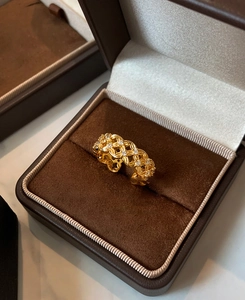 Detailed macro view of gold-plated hollow crisscross ring with zircons in a luxury box