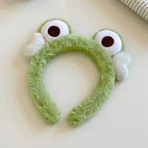 Gros plan d'un bandeau grenouille en peluche verte avec de grands yeux rigolos