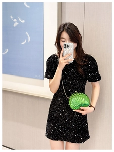 Mirror selfie showing a green shell clutch bag with gold chain and sequin dress