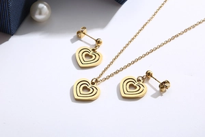 Flat lay of gold hollow heart necklace and earrings set with gift box and pearl decor