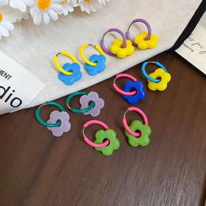Close-up of colorful resin flower hoop earrings set on a natural wooden background