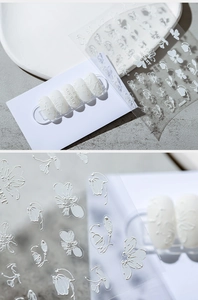 Detaillierte Makroansicht von 3D-Präge-Nagelstickern mit weißen Blumen und 3D-Anwendung