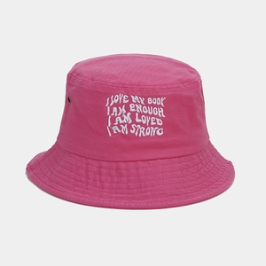 Close-up of pink bucket hat featuring white letter embroidery and metal eyelet details