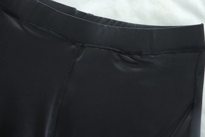 Close-up of black high-waisted yoga pants waist seam and smooth synthetic fabric texture