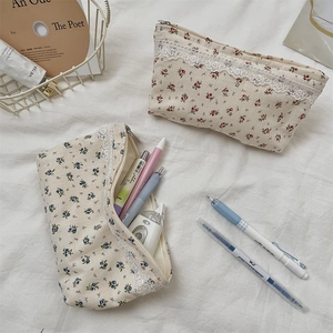 Detail of floral canvas pouches with delicate white lace trim and metal zipper closure