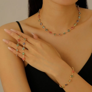 Golden clover jewelry set with multicolor enamel flowers worn by a female model