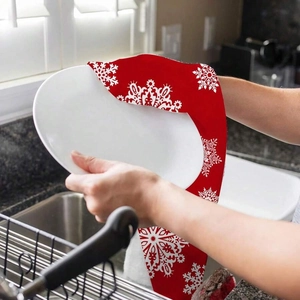 Detail of red Christmas kitchen towel with snowflake pattern used to dry a white plate