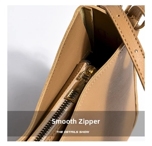 Close-up of golden metal zipper and internal compartment structure of khaki leather bag
