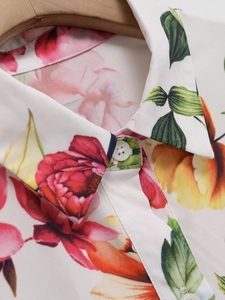 Détail d'une robe à fleurs colorée avec col net et bouton blanc sur le tissu