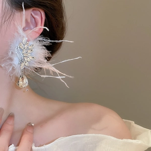 Detailed view of wing-shaped crystal earring with white feathers and teardrop pendant