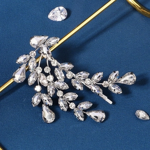 Detail of silver leaf hair clip with clear crystals on a blue textured background