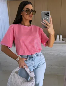 Détail du t-shirt à rayures roses et oranges avec un sac à main tissé blanc élégant