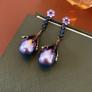 Macro detail of retro flower earrings with blue zircons and purple teardrop pearl