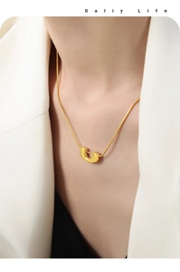 Gros plan d'un collier chaîne serpent dorée avec pendentif en U sur le mannequin