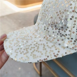 Detailed close-up of golden sequins on white mesh lace fabric of a baseball cap