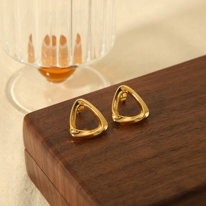 Detail of 18k gold hollow triangle geometric stud earrings on a walnut wood display box