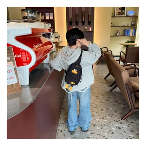 Vista posteriore di un bambino con borsa a tracolla a forma di papera nera