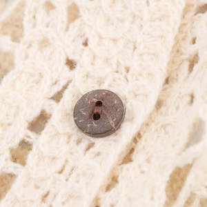 Dettaglio di un cardigan in maglia beige con un bottone in legno naturale marrone scuro