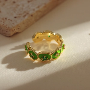 Macro detail of adjustable gold floral ring with green enamel and clear zircon stones