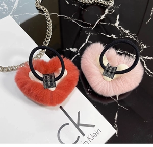 Detailed macro view of heart-shaped plush hair ties in red and pink with hand-made labels