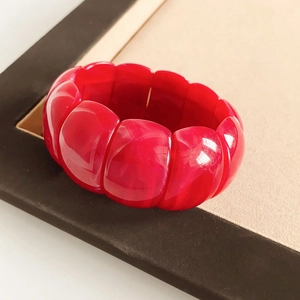 Macro shot of polished red acrylic geometric stretch bracelet sections on a premium tray