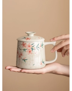 Macro detail of hand-painted pink cherry blossom on beige ceramic mug with lid