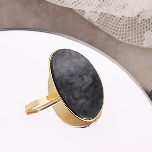 Detail of gold open ring with oval black marble inlay on a reflective mirror surface