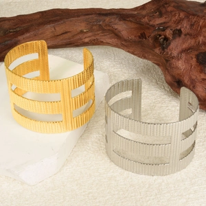 Detailed view of hollow stair-step textured bangles in gold and silver on stone