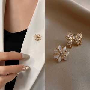 Detailed macro view of daisy and bow brooches with cat's eye stones and sparkling zircons