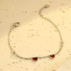 Double-layered silver stainless steel bracelet featuring red enamel heart charms and beads
