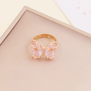 Close-up of a pink butterfly zircon ring with a golden adjustable band on a display tray