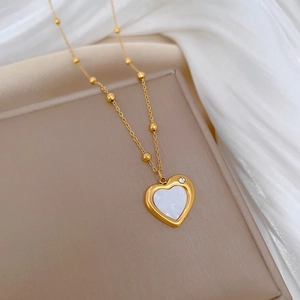 Close-up of golden heart pendant with white shell inlay and sparkling crystal detail