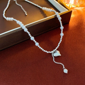 Macro detail of faux pearl choker with silver heart pendant and adjustable lobster clasp