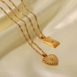 Vue macro de pendentifs cœur et rectangle dorés 18K avec texture soleil rayonnante