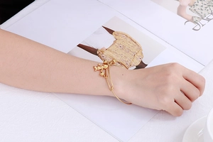Détail d'un bracelet en acier titane doré avec pendentif ours et petite clochette