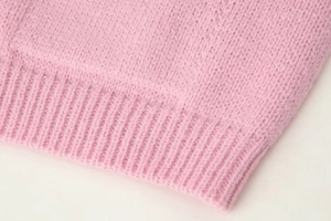 Close-up of pink knit sweater ribbing detail showing high-quality wool blend texture