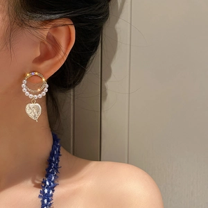 Detail shot of golden hoop earrings with pavé rhinestones and heart baroque pearl charms