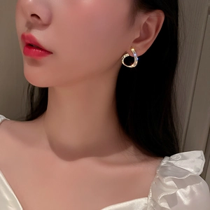 Close-up of golden hollow waterdrop earrings with inlaid diamonds on model ear