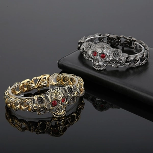 Gothic skull bracelet in gold and black finish with red stones on a luxury leather surface
