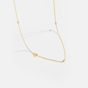 Macro detail of gold S925 silver letter A necklace with three inlaid sparkling zircon stones