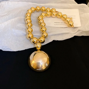 Close-up of chunky gold ball necklace with large mirror-polished round pendant