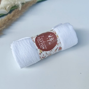 Detailed macro view of white pleated cotton scarf texture with handmade fashion paper label