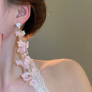 Close-up of pink floral tassel earrings with gold chains on a fashion model