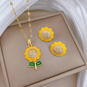 Golden sunflower jewelry set with yellow enamel and crystals on a beige display mat