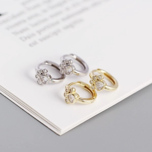 Close-up of cat paw earrings with heart-shaped zircon stones in gold and silver finish