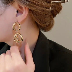 Dettaglio di orecchini a doppio cerchio geometrico dorati su modella per stile moderno